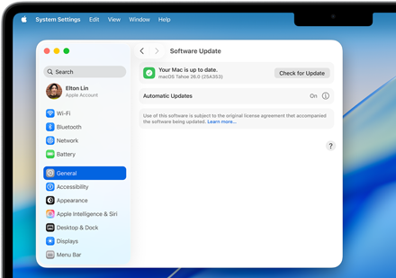 Una ventana de Configuración del Sistema muestra el mensaje 'Tu Mac está actualizada' con macOS Tahoe 26.0 en una MacBook Pro de 14 pulgadas