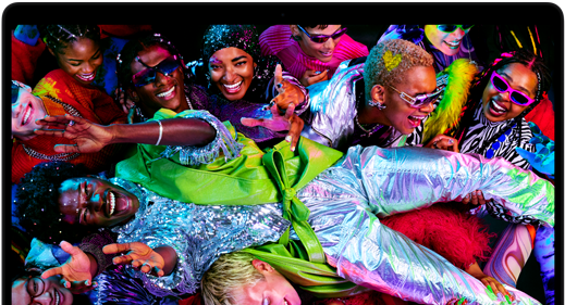 Imagen colorida de una persona en posición horizontal siendo sostenida por una multitud en una fiesta, destacando la brillante pantalla Liquid Retina XDR