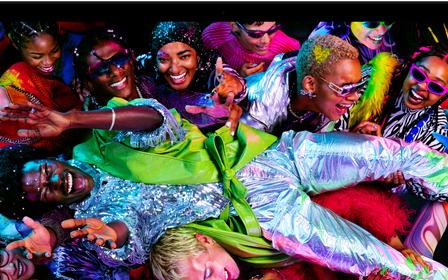 Imagen colorida de una persona en posición horizontal siendo sostenida por una multitud en una fiesta, destacando la brillante pantalla Liquid Retina XDR
